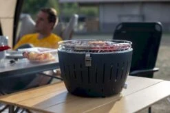 LotusGrill XL Hybrid Houtskoolbarbecue - Rood -Kampeer Verkoop lotusgrill in gebruik met toppy shirtje 2